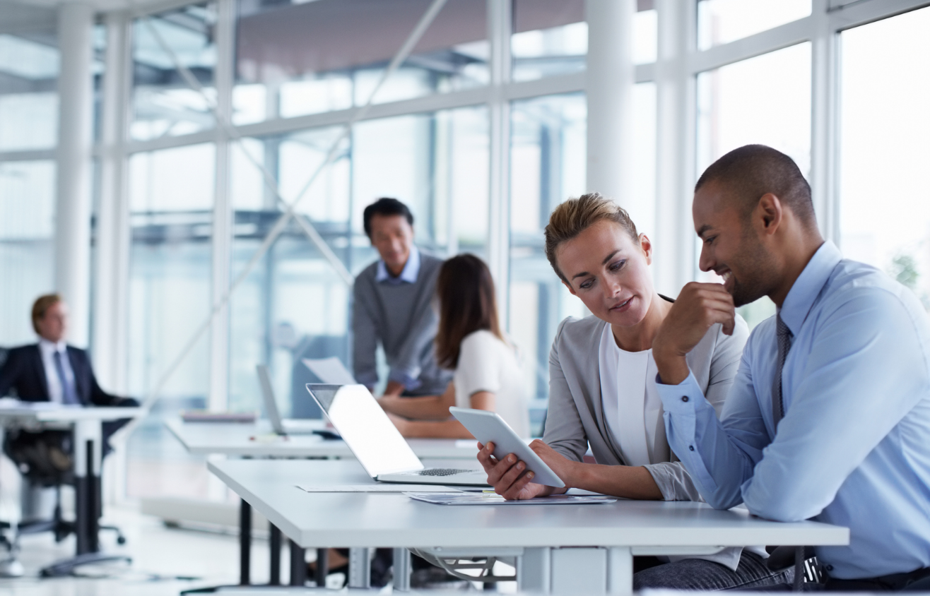 Black entrepreneur and woman at an office table viewing a tablet
